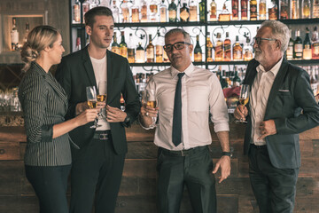 Group of  business partner celebrating their victory. Old business man making a toss to younger business man and woman. They are holding a champagne glass in a hotel lobby with city scape background.
