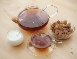 Black tea in a glass with milk in a pot and rock candy sugar 
