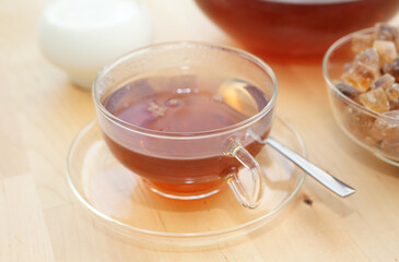 Black tea in a glass with milk in a pot and rock candy sugar 
