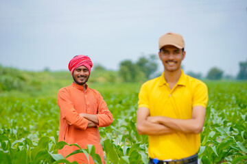 Indian agronomist with farmer at green agriculture field.