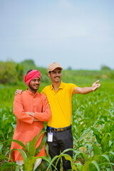 Indian agronomist with farmer at green agriculture field.