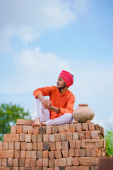 Indian farmer sitting on bricks and watching on sky