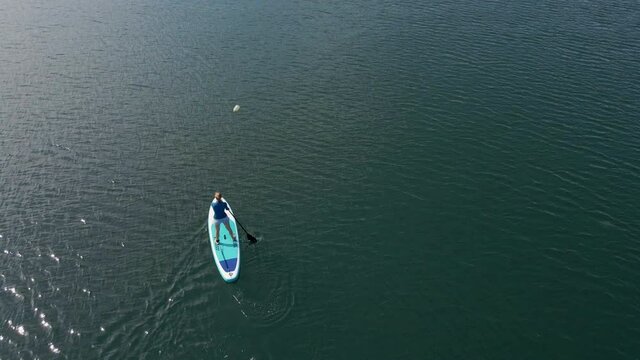 Aerial shot. Young women is having fun. Stand Up Paddling in the sea. SUP. Paddling among debrees of a sunk metal ships