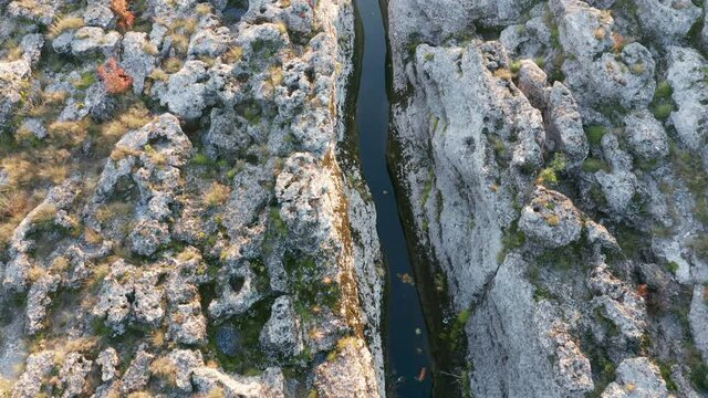 Narrow mountain river flowing through desolate rocky landscape. Stream bed cut deep into stones. Texture of rough barren terrain on the banks of Cijevna (Cem) in Montenegro. Aerial footage.