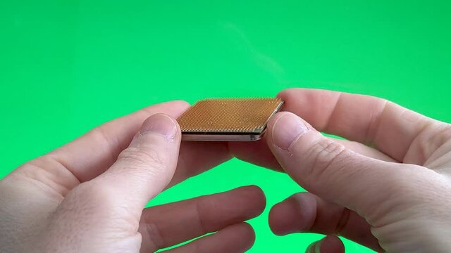 Vision of a microchip in the hands of a person examines how electronic manufacturing is, with a green background.