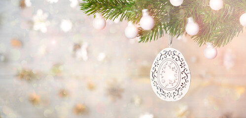 White Christmas decoration on tree and blurred background in gold color.