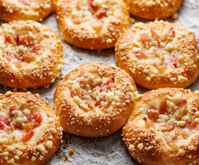 Yeast sweet rolls with rhubarb and butter crumble on baking paper close-up