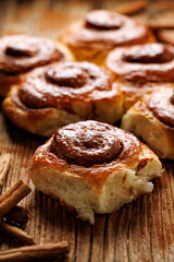 Homemade sweet cinnamon buns on a wooden table, close up view