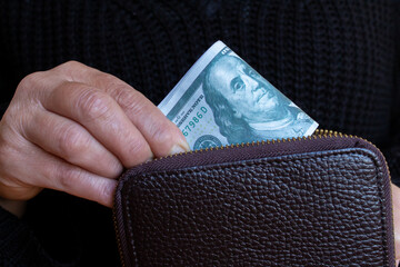 Woman puts dollar bills in wallet.