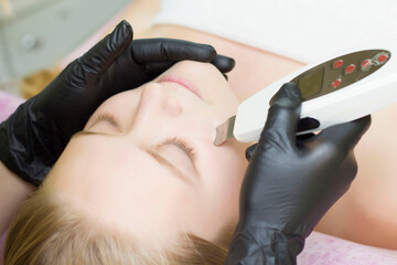 Close up of a young attractive woman getting ultrasonic facial skin cleansing treatment by professional cosmetologist beautician dermatology cosmetology skincare clean fresh rejuvenation wellness.