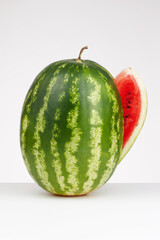 Whole of ripe watermelon with slice on a white background, fresh fruit. Cut red watermelon. Shallow depth of field