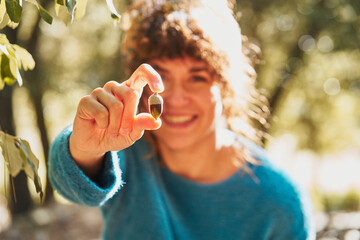 Happy woman showing acorn in nature
