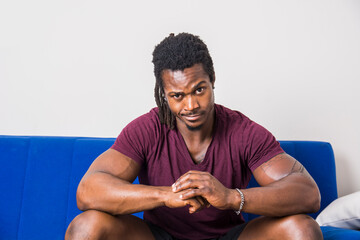Muscular black man sitting on blue couch
