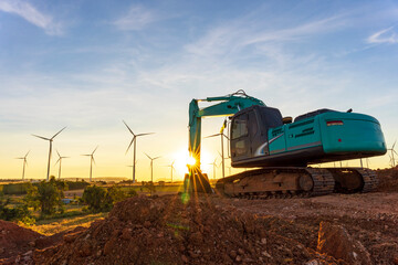 Backhoe and wind turbines that are generating electricity in the background, the concept of...