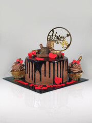 Chocolate cake with fresh chocolates decorated as topping, red edible hearts and chocolate ganache