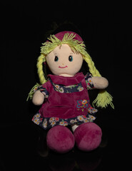 A rag doll with yellow hair, wearing a purple dress with flowers on it