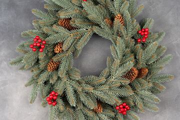 top view of decorative festive wreath with red winter berries and pine cone.