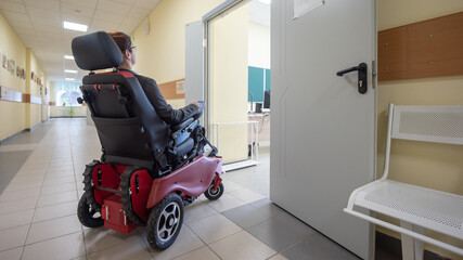 Caucasian woman in electric wheelchair in university corridor.
