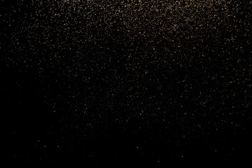 Black festive background. Abstract scattering of gold sparkles on black. Holiday backdrop
