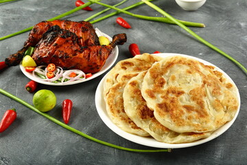 Whole wheat Indian layered flat bread- paratha, served with tandoori chicken. - obrazy, fototapety, plakaty