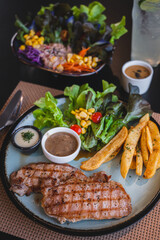 Grilled pork steak and pepper sauce with french fries and salad.