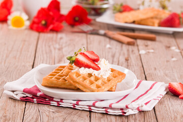 Waffles with strawberries and whipped cream.