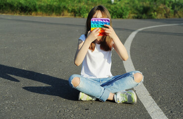 Girl plays the toy pop it outdoors.