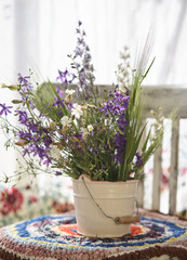 Still life with fresh wild flowers in vase on vintage chair
