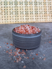 Fototapeta na wymiar Pink himalayan rock coarse salt in a gray boel on gray background