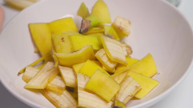 A person making banana peel fertilizer with banana cuts. A woman hand cutting banana skin into small pieces