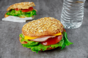 Whole grain sandwiches with ham, tomatoes and lettuce.