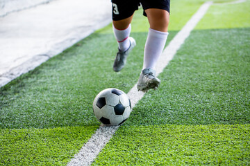 Selective focus to soccer ball with blurry soccer player run to shoot it.
