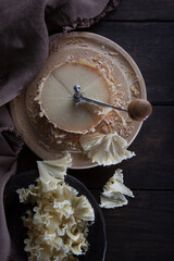 The tete de moine cheese is cut into thin shavings. Special girolle knife. Photo on black background. Brown cotton napkin. View from above.