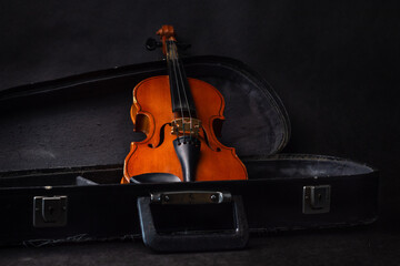 An old violin in a case. Dark background. Selective focus