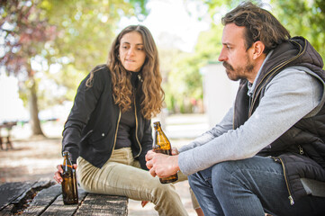 Couple in quarrel, boyfriend and girlfriend drinks beer from bottle