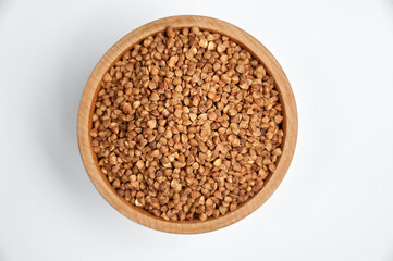 Naklejka premium buckwheat grains in a wooden bowl on a white background