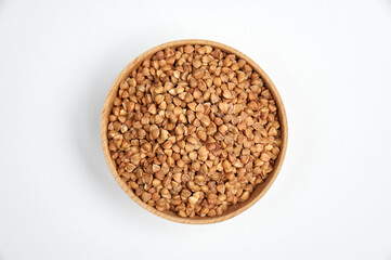 buckwheat grains in a wooden bowl on a white background