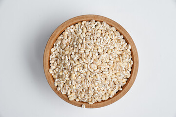 pearl barley grains in a wooden bowl on a white background