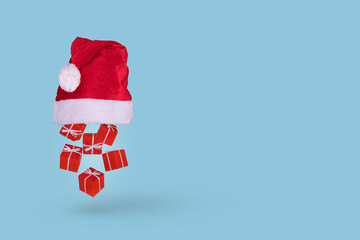 Creative idea with Santa hat and red Christmas gift box falling on blue background. Happy holidays. New year minimal concept.