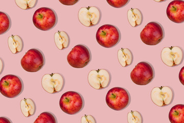 Outstanding pattern of fresh whole apple and halves on  pastel pink background.