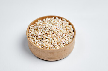 pearl barley grains in a wooden bowl on a white background