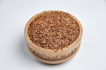 flax grain in a wooden bowl on a white background