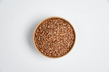 flax grain in a wooden bowl on a white background