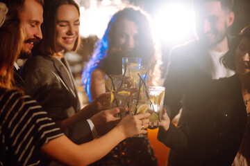 Cheering and drinking cocktails. Group of people partying in a nightclub and toasting drinks with cocktails. Party, celebration, drink, birthday concept.