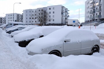 Cars covered with snow after snowstorm are standing in the street in town