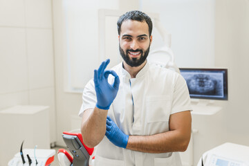 Confident Arabian male stomatologist dentist showing okay gesture looking at camera at dental...