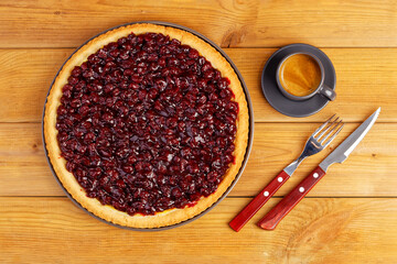 Homemade berry pie with cherry and cup of coffee espresso on wooden table. Top view.