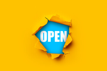Bright yellow torn paper inside a hole with the inscription Open on a blue background.