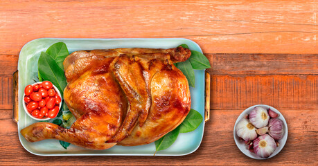 Half roast chicken on tray with cherry tomatoes, bay leaves and garlic.