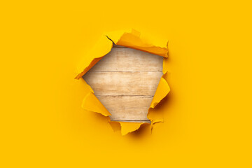 Bright yellow torn paper inside in a hole wood background.